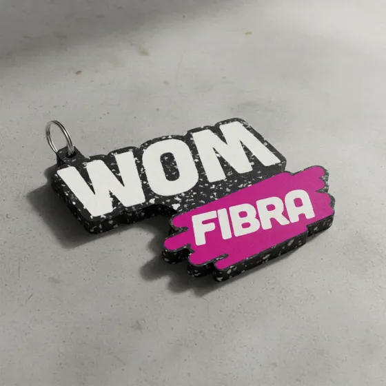 Llavero de plástico reciclado cortado con la forma del logo de WOM Fibra